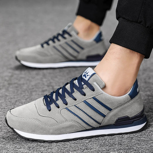 Gray sneakers with blue accents worn by a person on a gray background