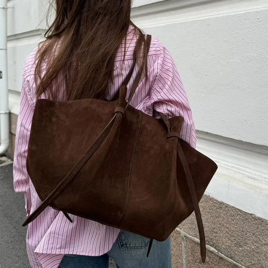 Person wearing a brown leather backpack with a blurred background