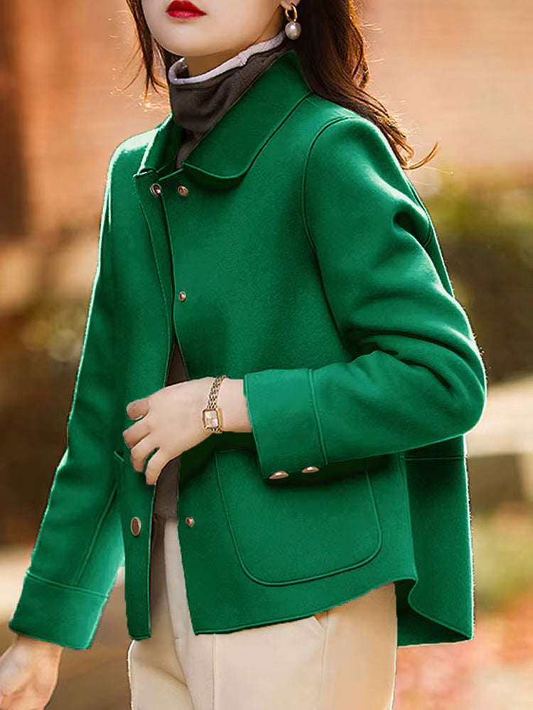 Person wearing a green coat with a blurred outdoor background