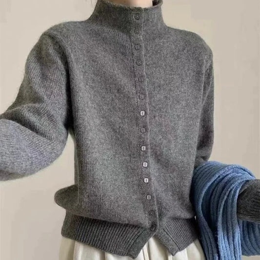 A gray knit mock-neck cardigan sweater with a button-down front, shown on a model with a blue knit scarf draped over one arm against a plain beige background.