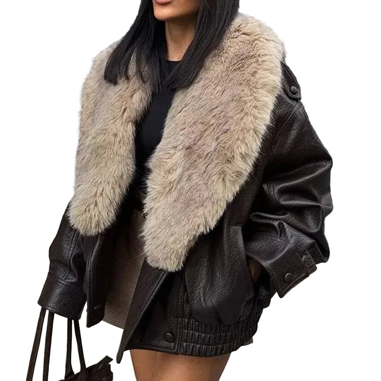 A woman wearing an oversized dark brown faux-leather jacket with a large beige faux-fur collar, paired with a black top and shorts, against a plain white background.