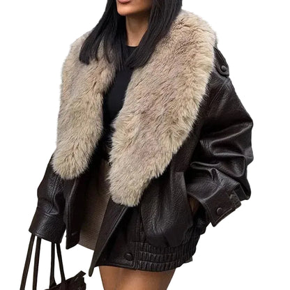 A woman wearing an oversized dark brown faux-leather jacket with a large beige faux-fur collar, paired with a black top and shorts, against a plain white background.