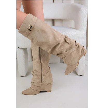 Beige knee-high boots worn by a person sitting on a white chair.