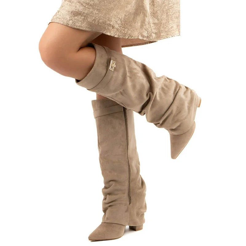 Beige knee-high boots worn with a beige skirt on a white background