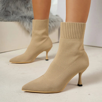 Beige sock boots with high heels on a neutral background