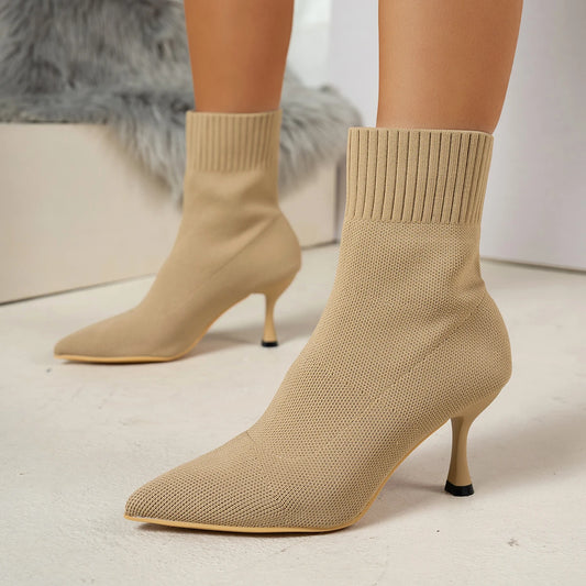 Beige sock boots with high heels on a neutral background