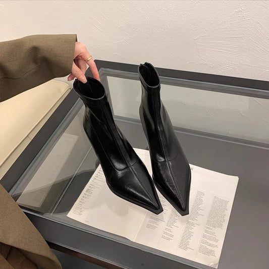 Black high-heeled boots on a glass table with a neutral background
