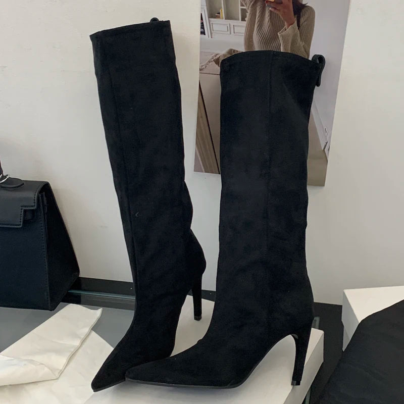 Black knee-high boots on a white surface with a blurred background