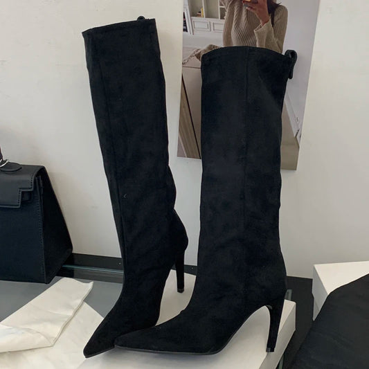 Black knee-high boots on a white surface with a blurred background