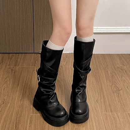 Black knee-high boots worn indoors on a wooden floor.
