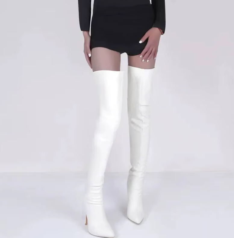 Black leather knee-high boots worn by a person on a light wooden floor.1