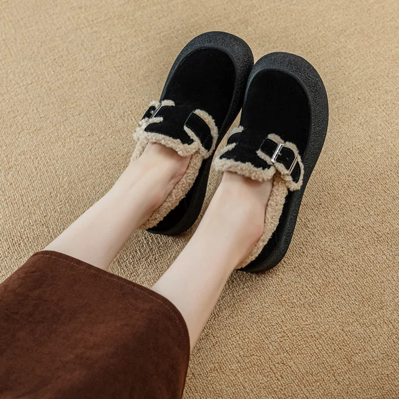 Black slippers with beige trim worn by a person on a beige carpet