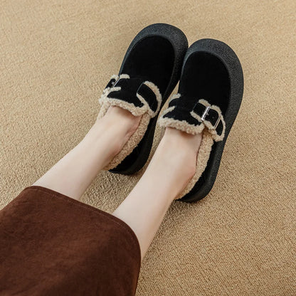 Black slippers with beige trim worn by a person on a beige carpet