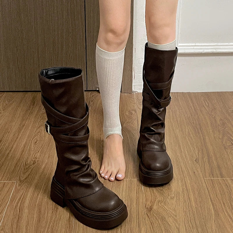 Brown knee-high boots worn with white socks on a wooden floor.