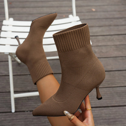 Brown knit ankle boots being held on a wooden floor.