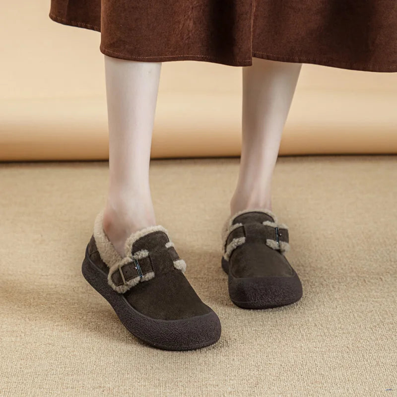 Brown shoes with fur trim worn by a person on a beige carpet