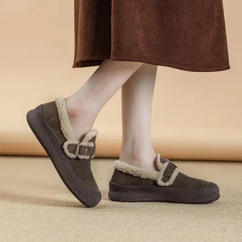 Brown slippers with fur trim worn by a person on a beige background