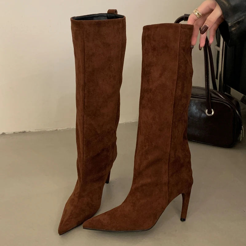 Brown suede knee-high boots on a neutral background