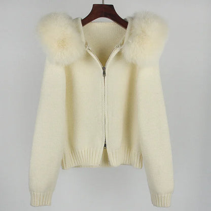 Cream-colored cardigan with fur trim on a hanger against a gray background