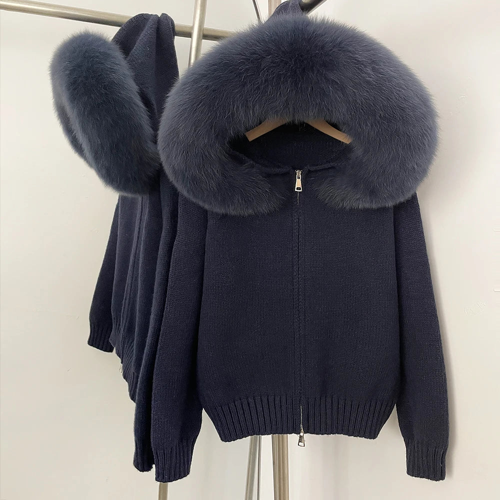 Dark blue knit jacket with large fur collar on a hanger against a white background