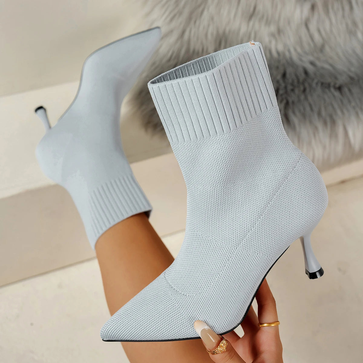 Light blue sock boots with high heels on a neutral background
