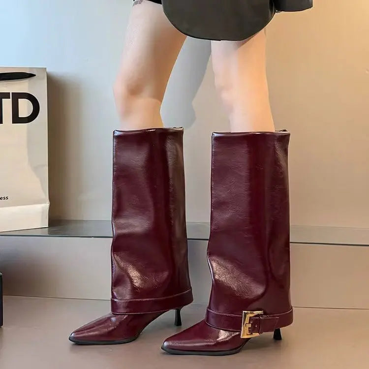 Maroon knee-high boots with a gold buckle worn by a person, with a neutral background.