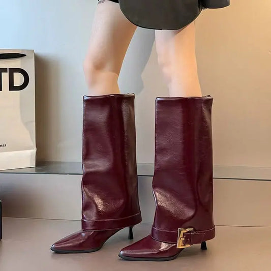 Maroon knee-high boots with a gold buckle worn by a person, with a neutral background.