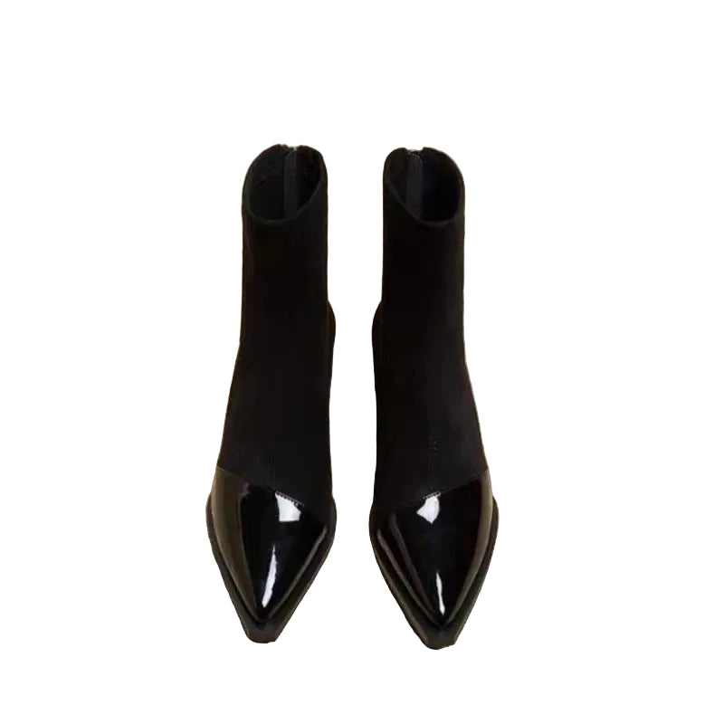 Pair of black pointed-toe boots on a newspaper background