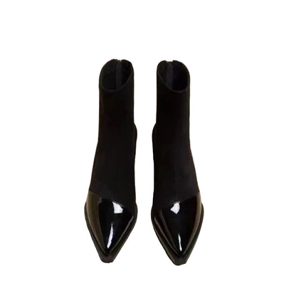 Pair of black pointed-toe boots on a newspaper background