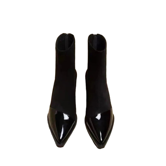 Pair of black pointed-toe boots on a newspaper background