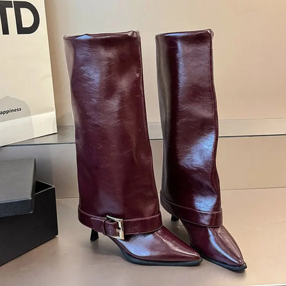 Pair of brown knee-high boots with a buckle on a light background