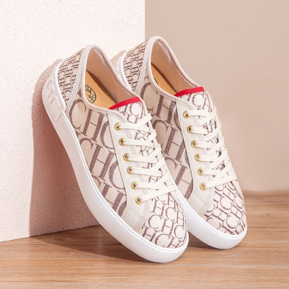 Pair of white sneakers with beige pattern on a wooden surface