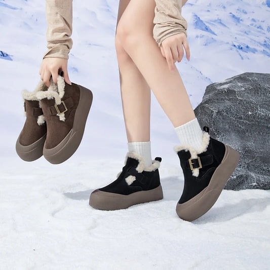 Person wearing black and brown winter boots with fur trim on a snowy background