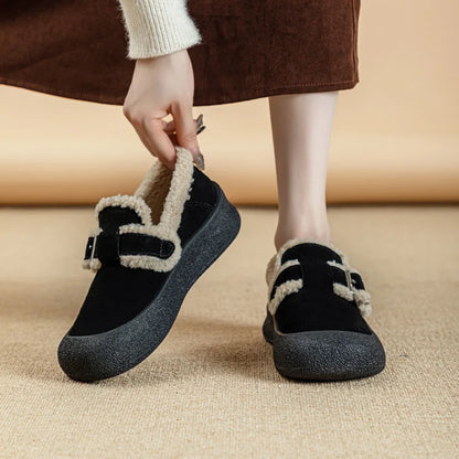 Person wearing black slippers with fur trim on a beige floor.