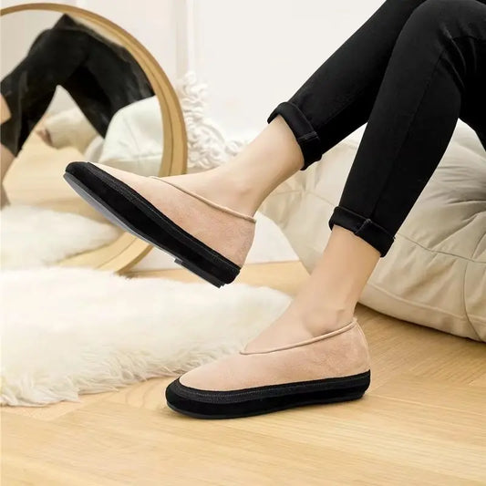 Person wearing pink loafers with black soles on a wooden floor.