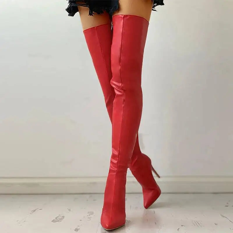 Red over-the-knee boots worn by a person on a light wooden floor.