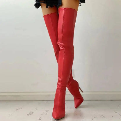 Red over-the-knee boots worn by a person on a light wooden floor.