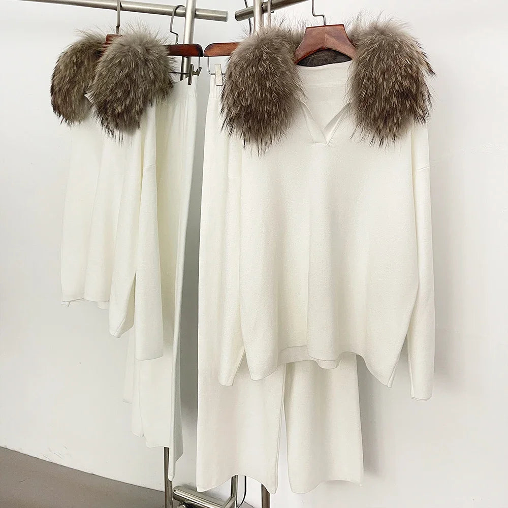 White sweaters with fur-lined hoodies on hangers against a white background