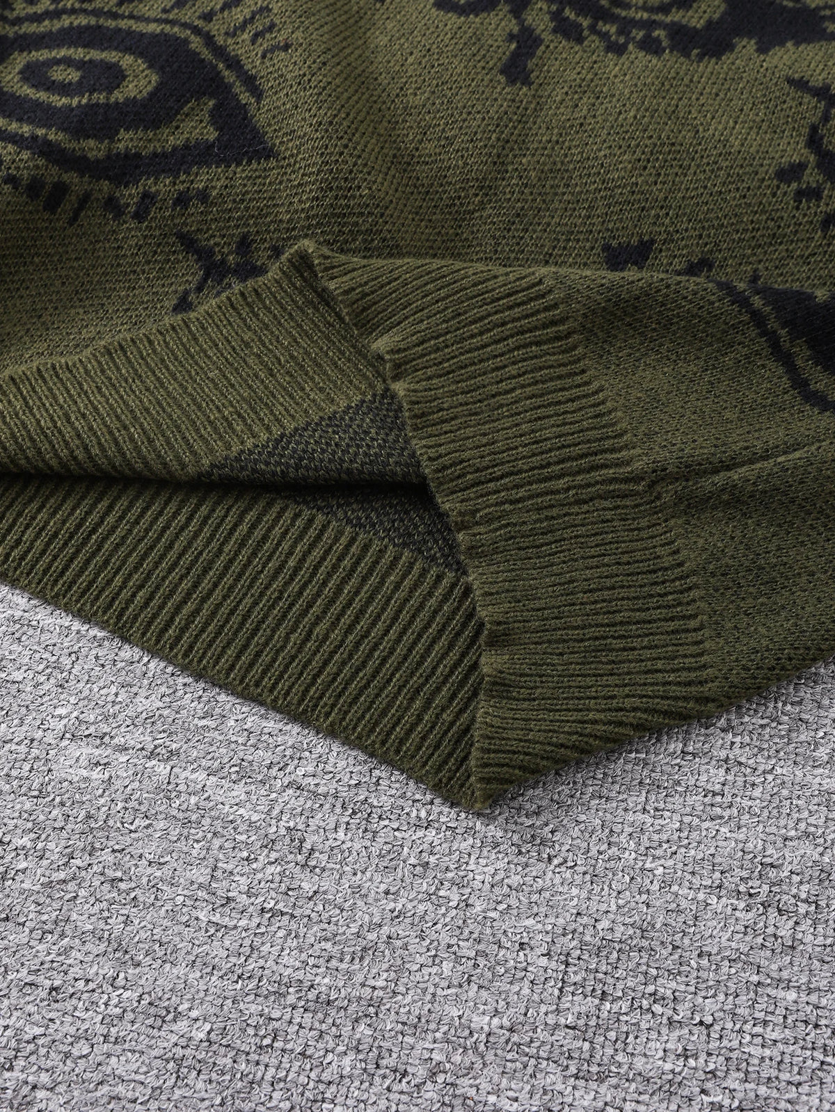 Green sweater with black patterns on a gray surface