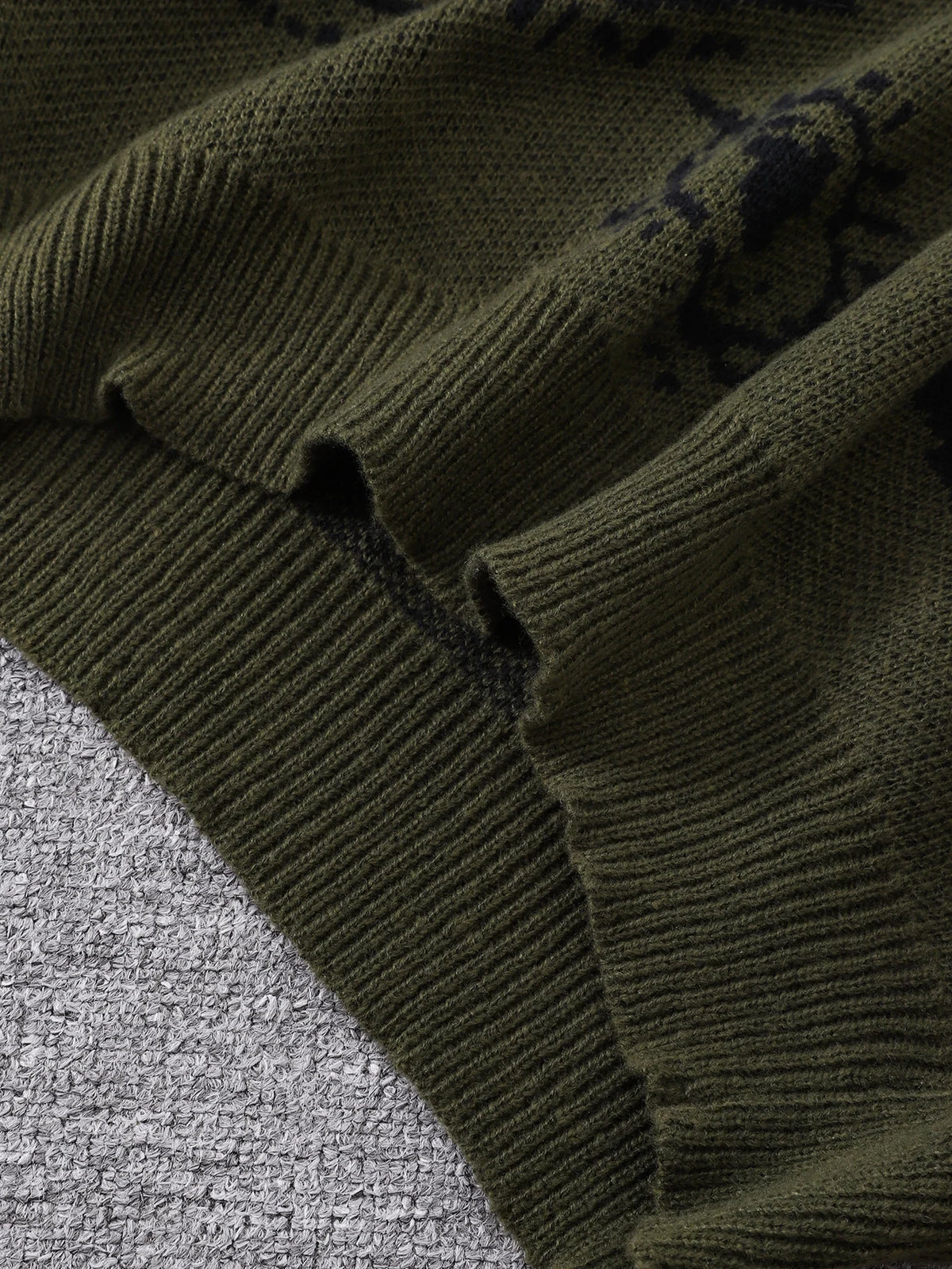 Close-up of a dark green knitted sweater on a textured surface