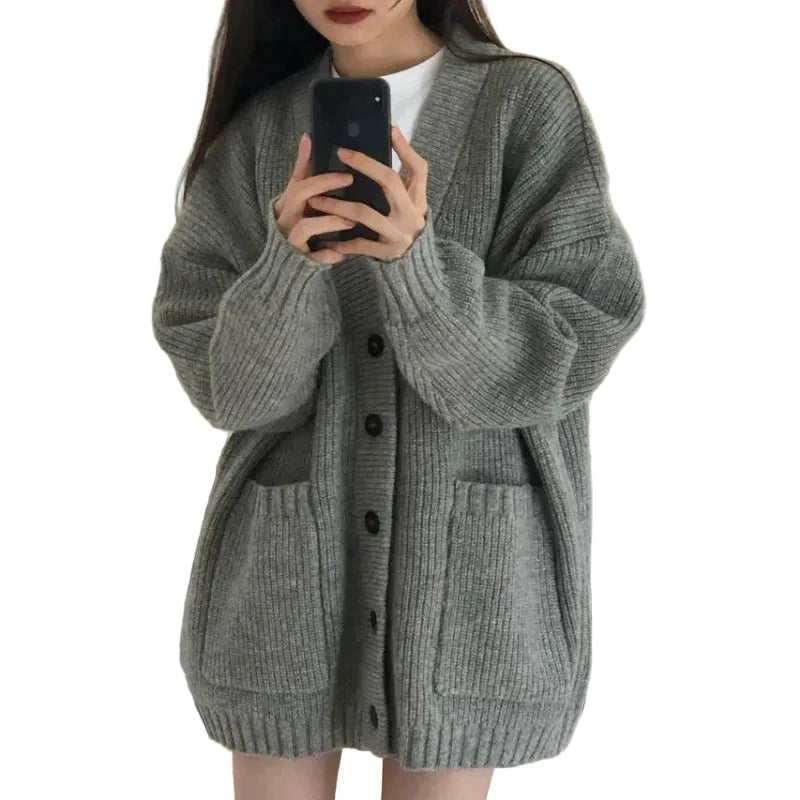 Person wearing a gray cardigan taking a mirror selfie.