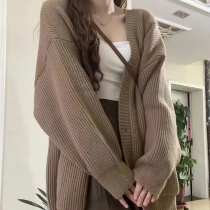 Person wearing a brown cardigan over a white top indoors.