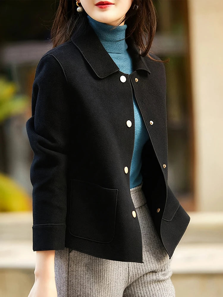 Person wearing a black coat with white buttons, blue sweater, and gray pants.