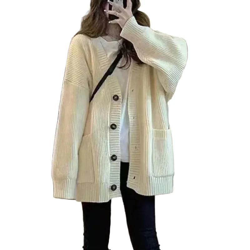 Person wearing a cream-colored cardigan taking a mirror selfie.