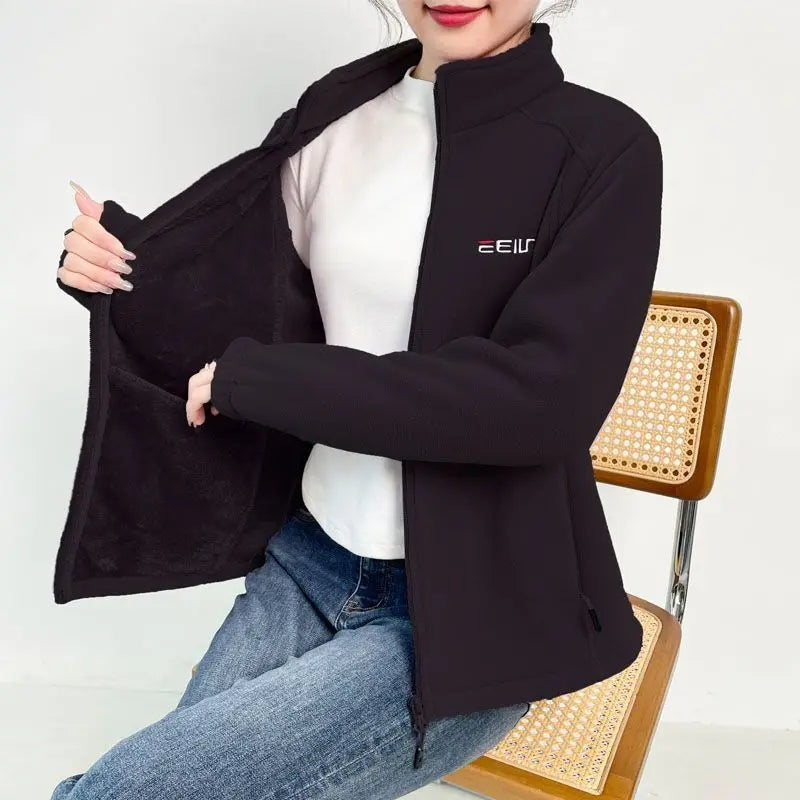 Person wearing a black jacket with a brand logo, sitting on a chair against a white background