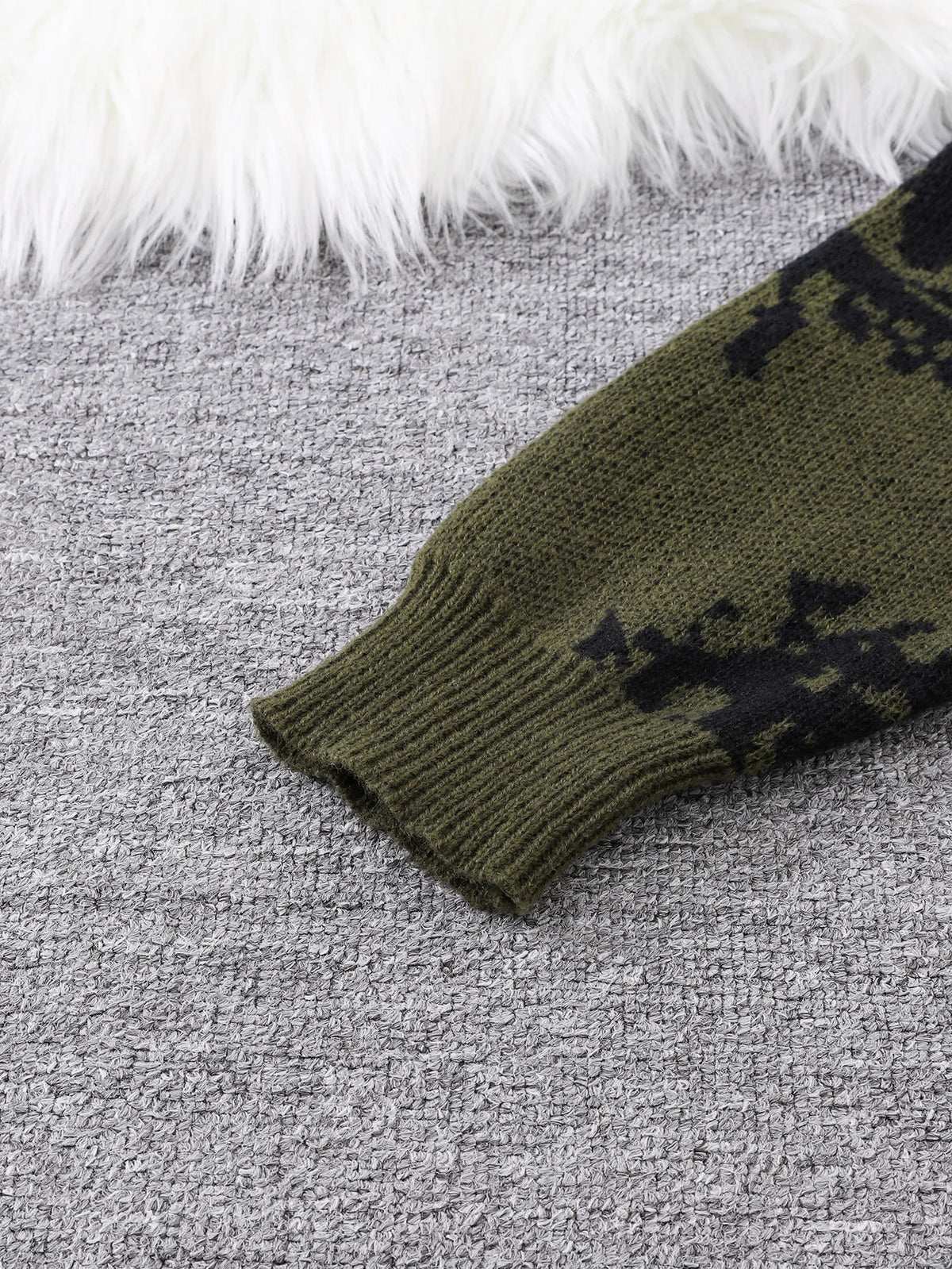 Green knitted sleeve with black pattern on a gray surface