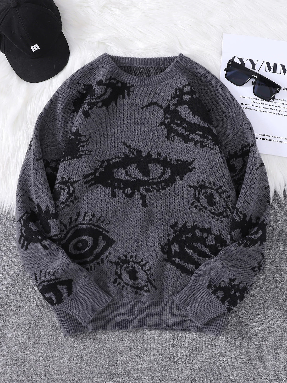 Gray sweater with black eye pattern on a gray surface