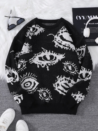 Black sweater with white eye pattern on a gray surface with white shoes and a book in the background.
