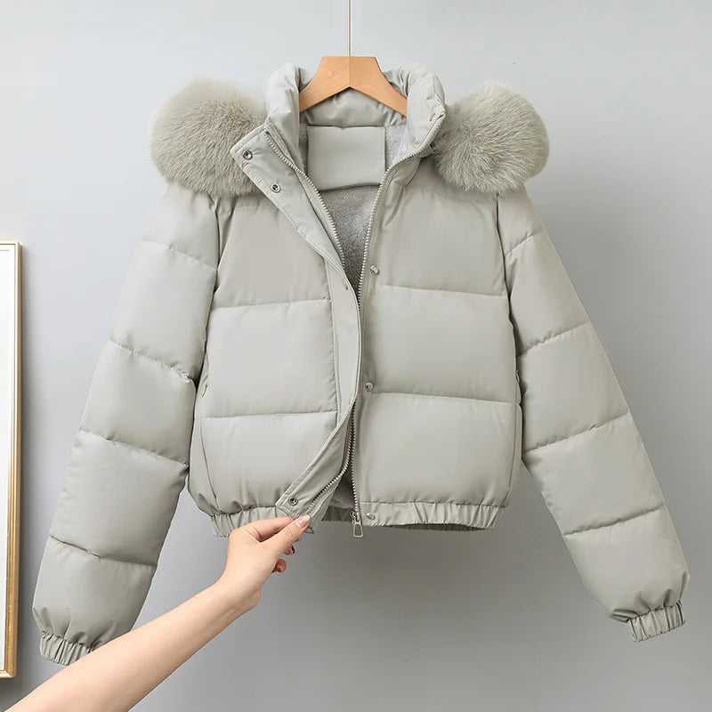 Light gray puffer jacket with fur-lined hood on a hanger against a gray background