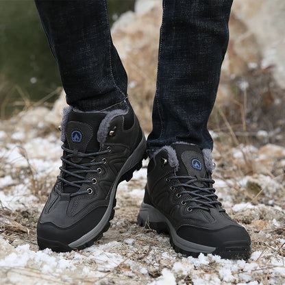 Gray hiking boots with fur lining worn by a person on a snowy ground.